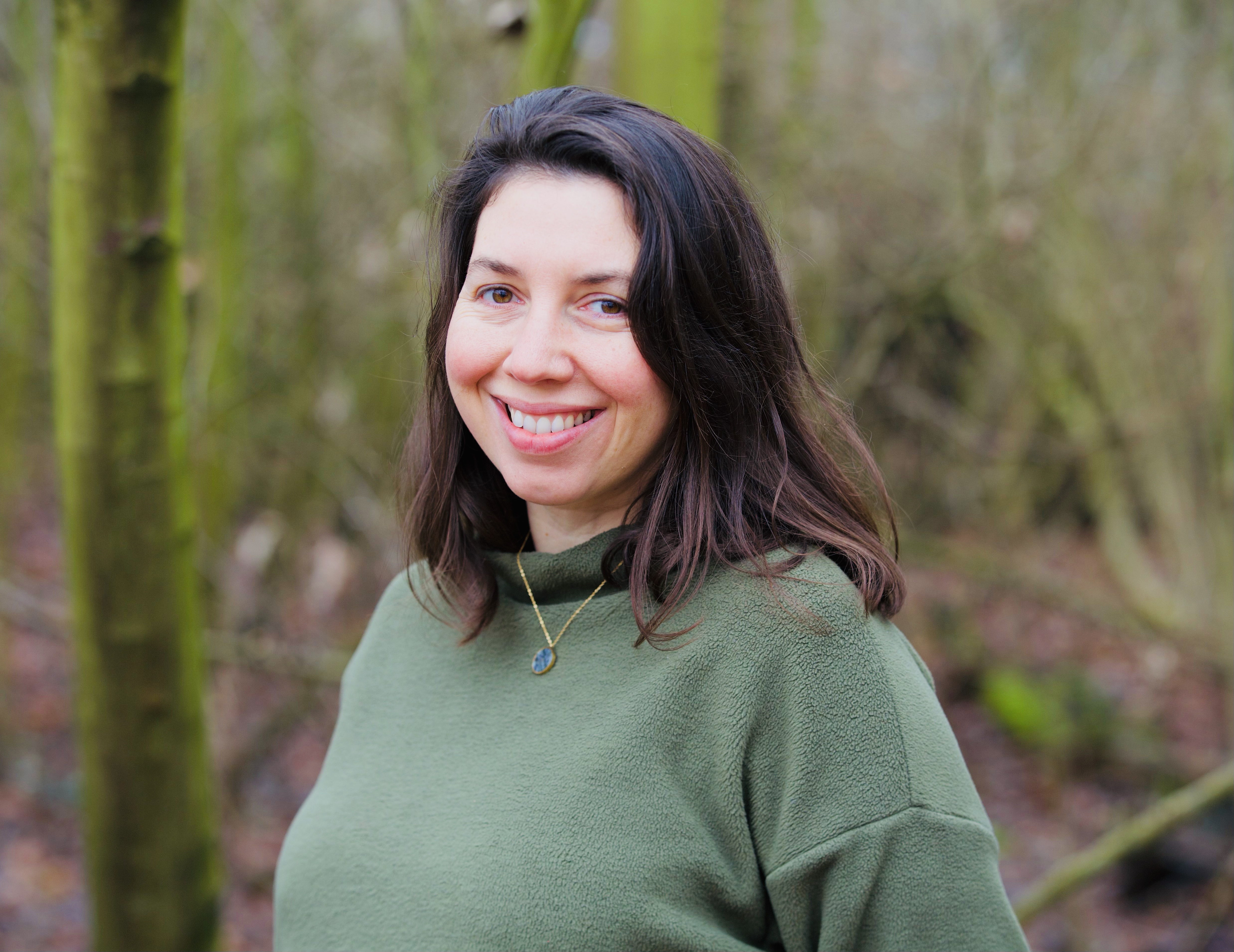 Image of Dr Rouas. She is wearing a bottle green fleece, with the woods in the background.