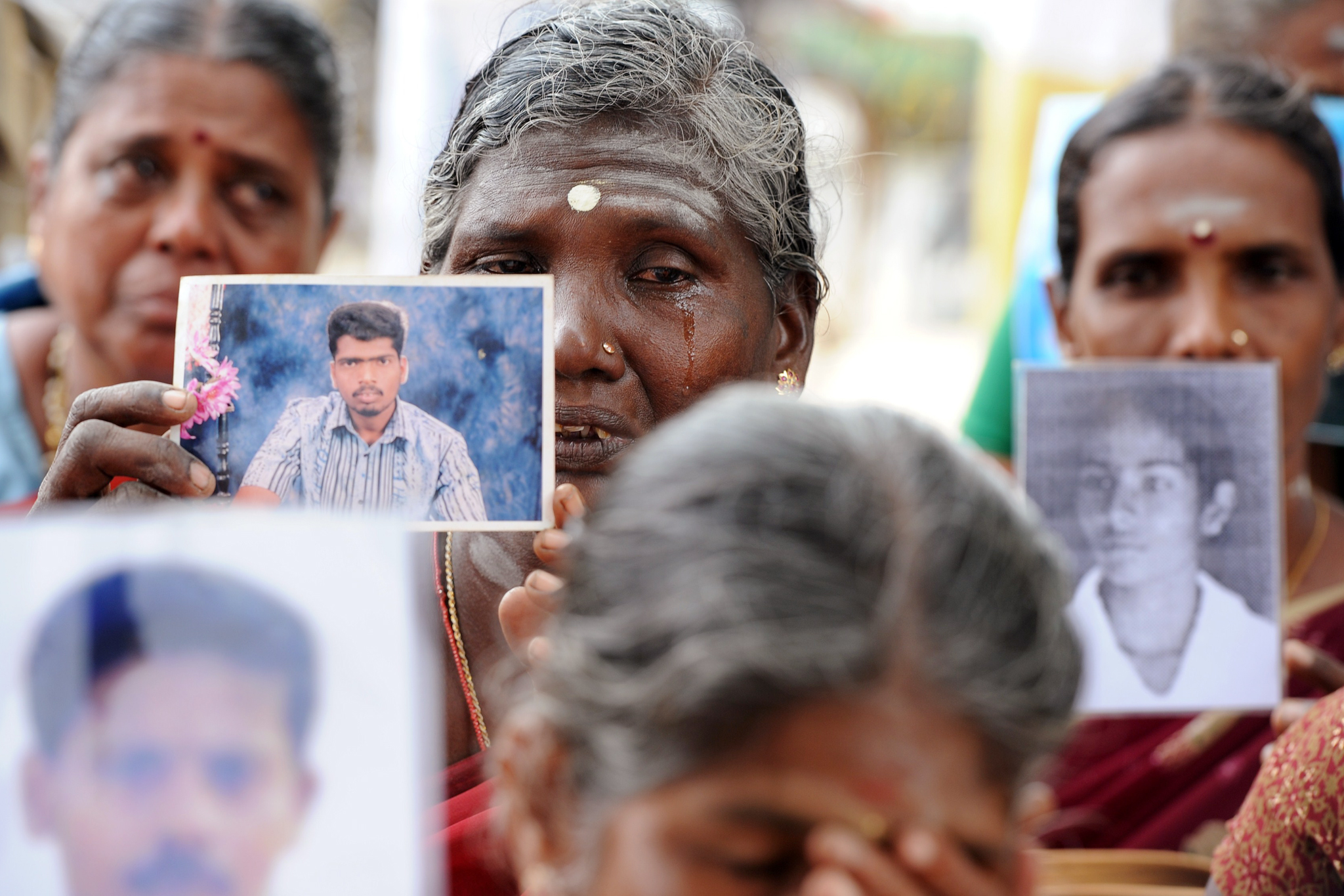 A woman in tears, holding the photo of her missing relative. 