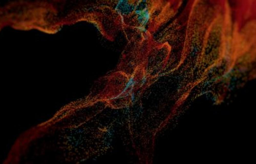 This image depicts a dynamic, colorful particle cloud with shades of red, orange, and blue against a black background, creating an abstract and vibrant visual effect.