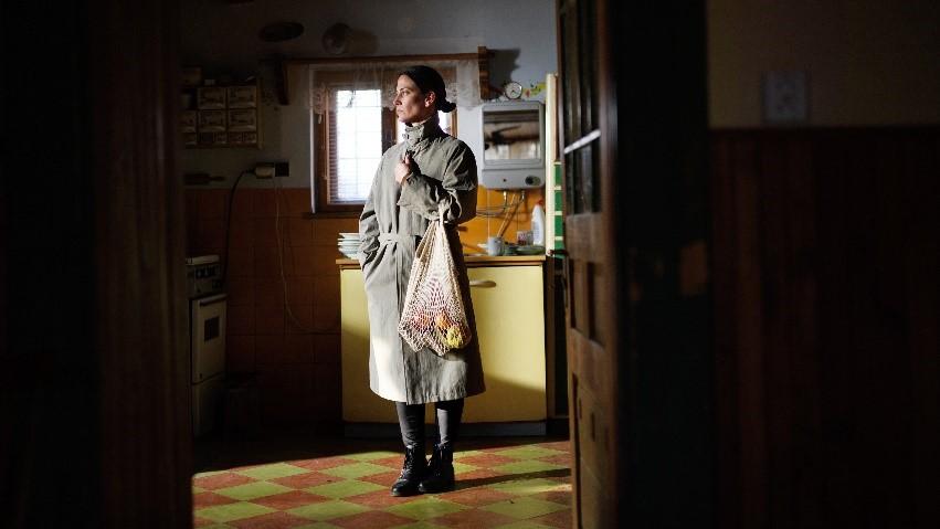 A woman standing in a kitchen holding a bag of groceries.