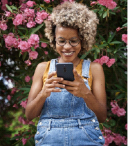 A woman standing in front of flowers using her phone
