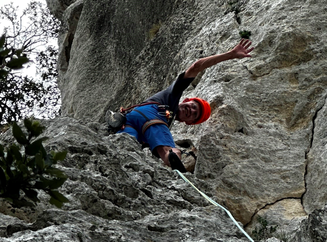 Photo of Horst Eidenmüller rock climbing and waving at the camera